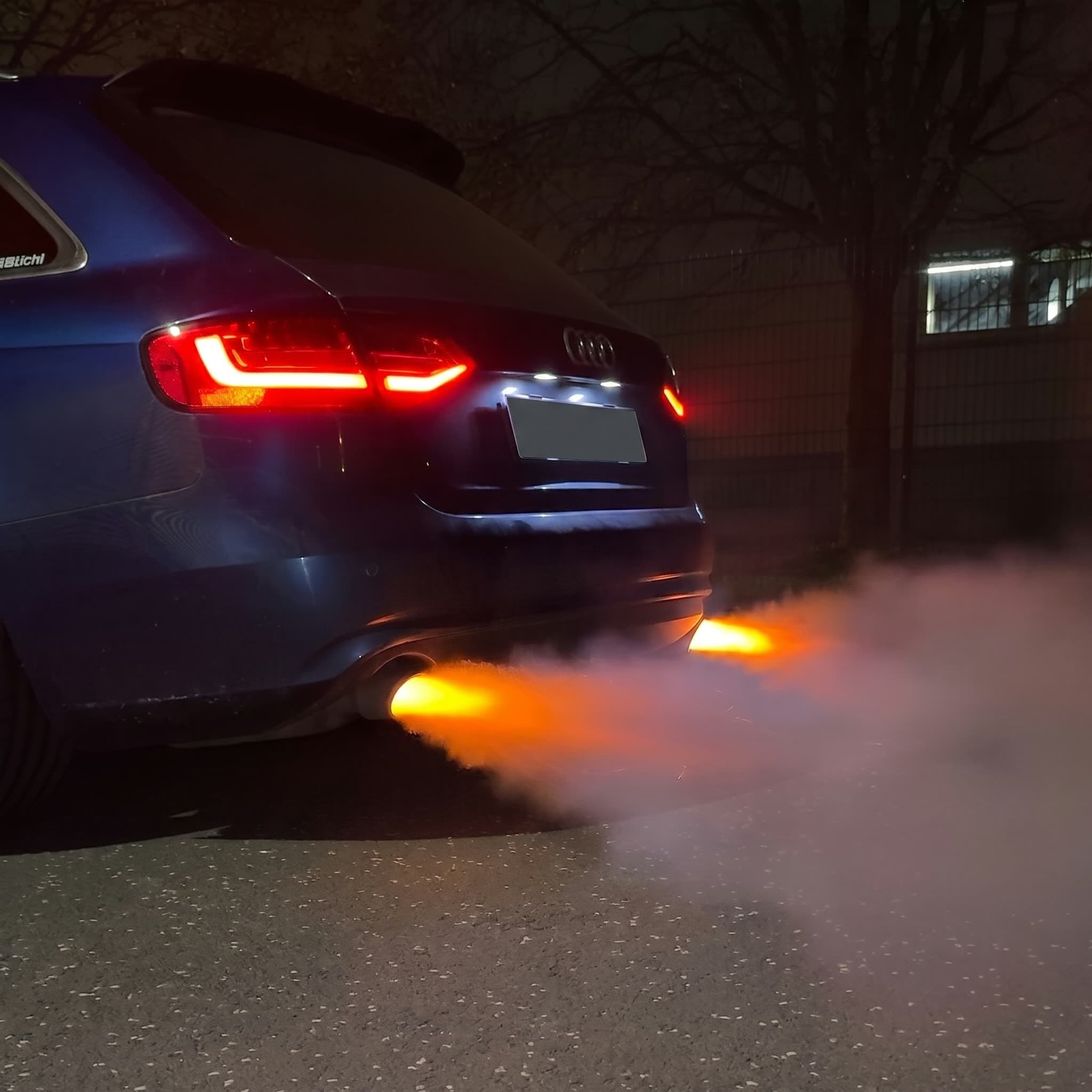 Auspuffflammen eines getunten Fahrzeugs bei Nacht
