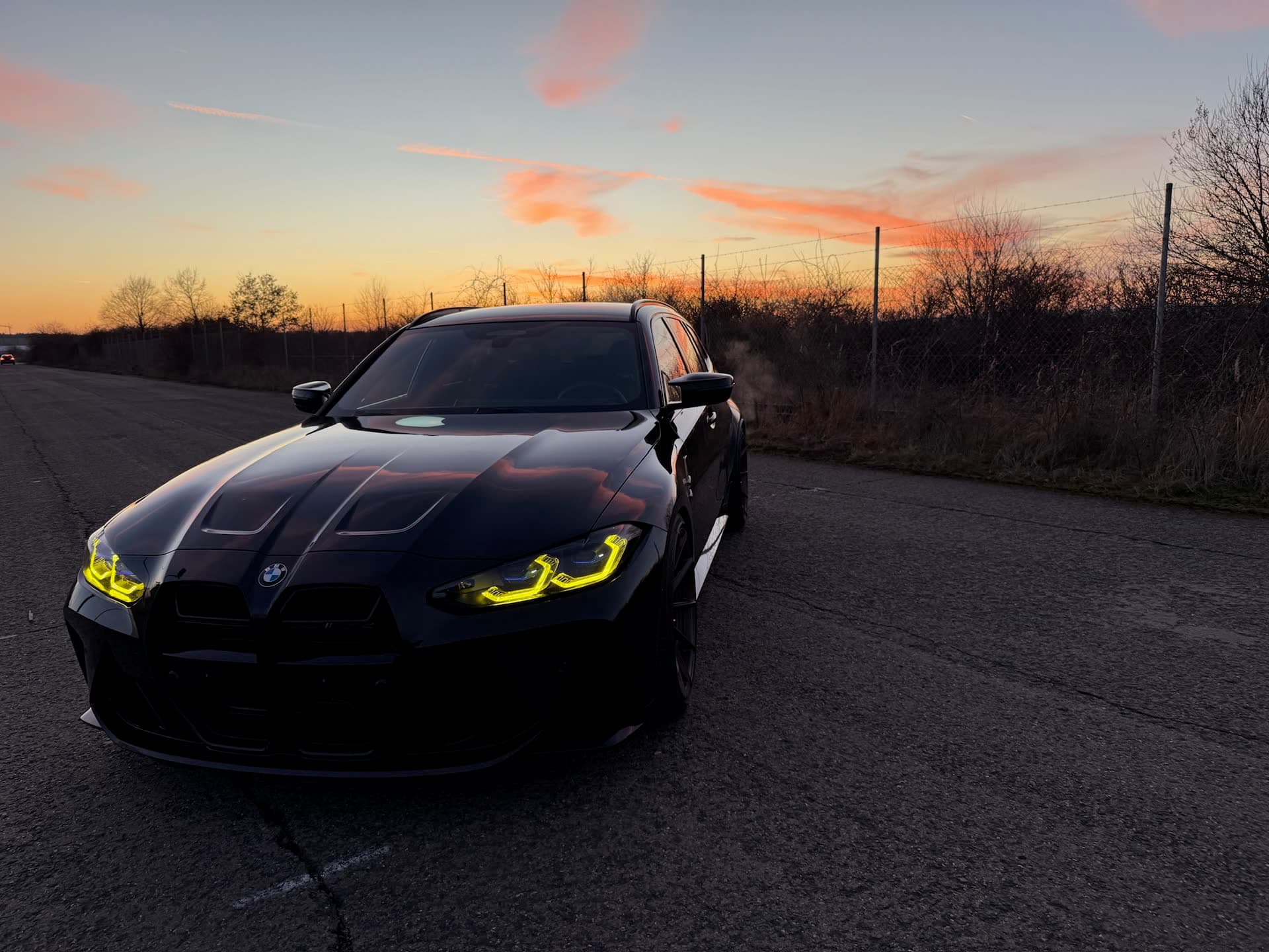 Optimierter BMW mit leuchtenden Tagfahrlichtern bei Sonnenuntergang